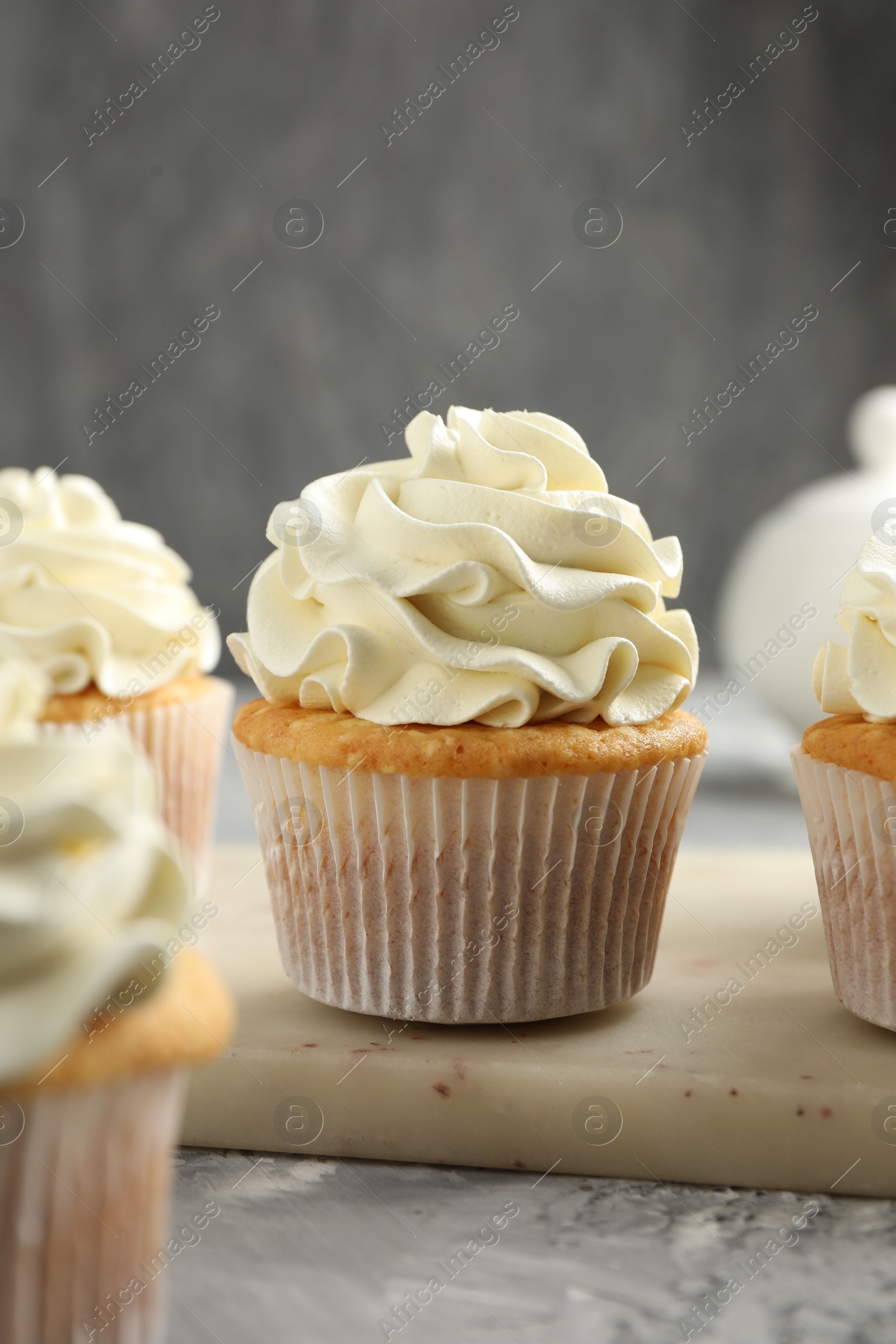 Photo of Tasty cupcakes with vanilla cream on grey table, closeup