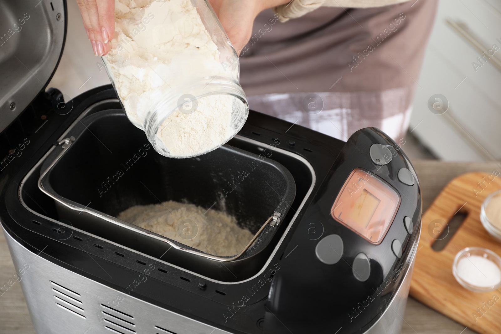 Photo of Making dough. Woman adding flour into breadmaker machine, closeup