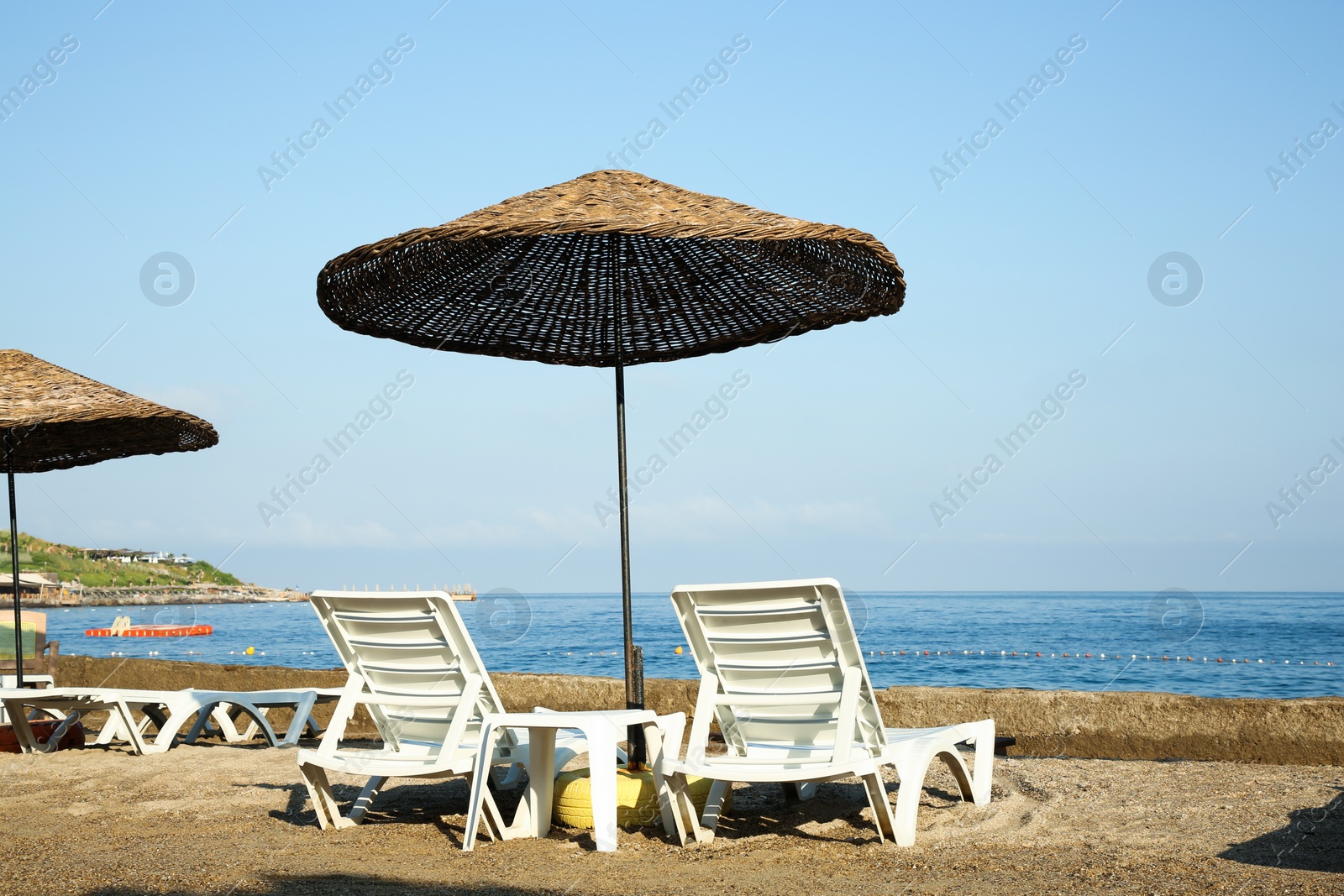 Photo of Two lounge chairs and beach umbrella on sea shore