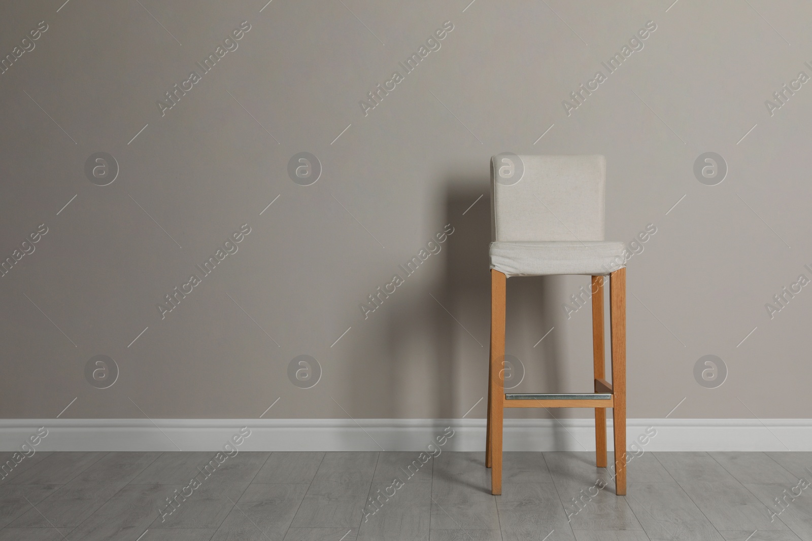 Photo of Stylish bar stool near light grey wall indoors. Space for text