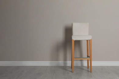 Photo of Stylish bar stool near light grey wall indoors. Space for text