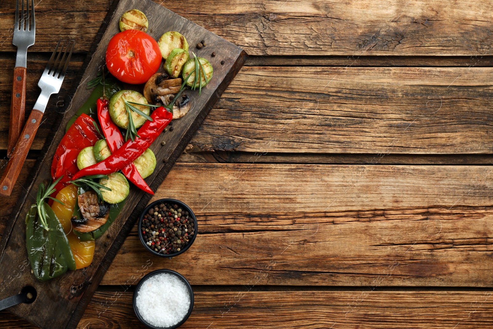 Photo of Delicious grilled vegetables served on wooden table, flat lay. Space for text