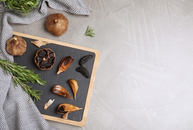 Photo of Flat lay composition with black garlic and space for text on grey table