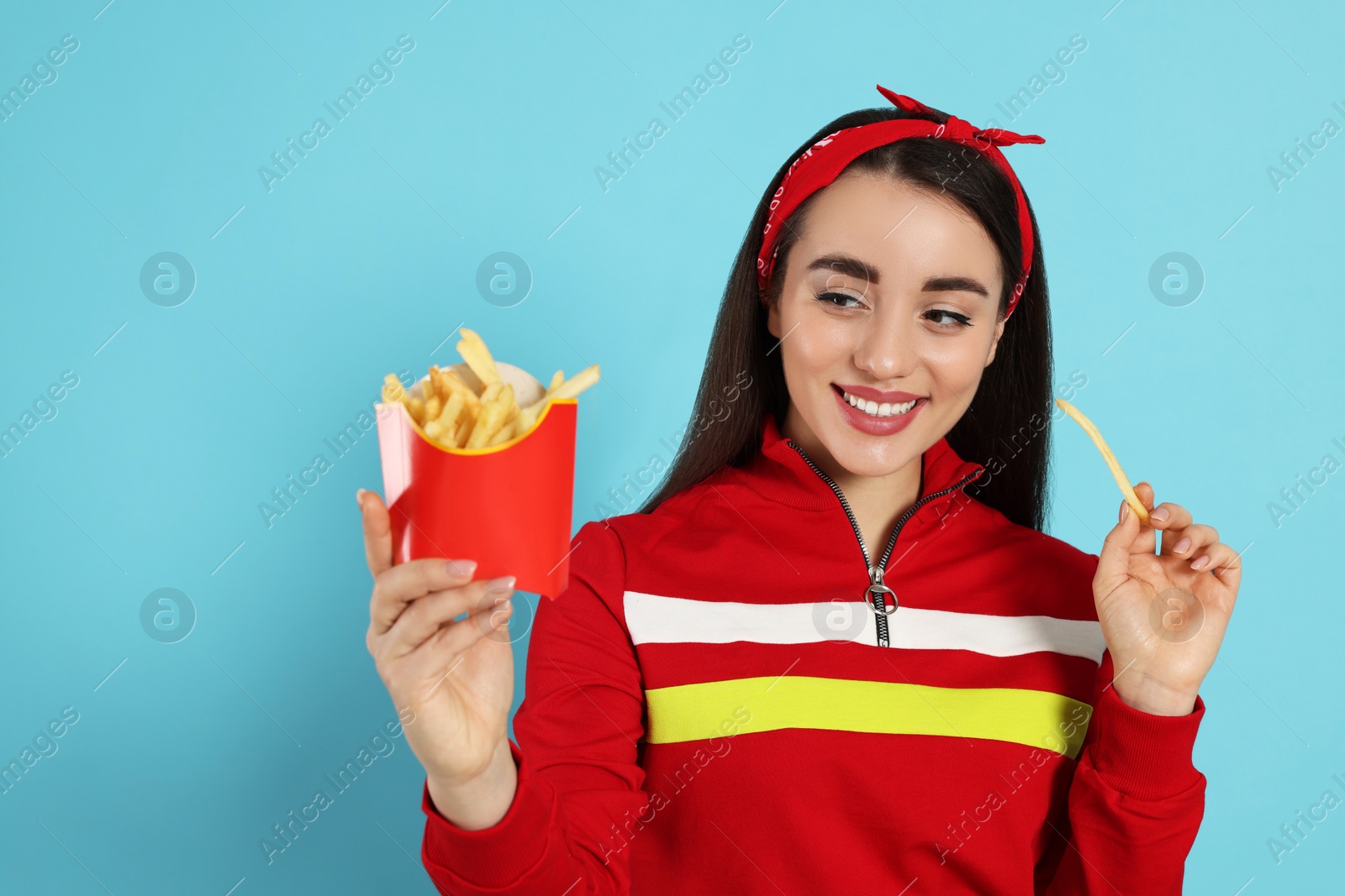 Photo of Beautiful young woman with French fries on light blue background