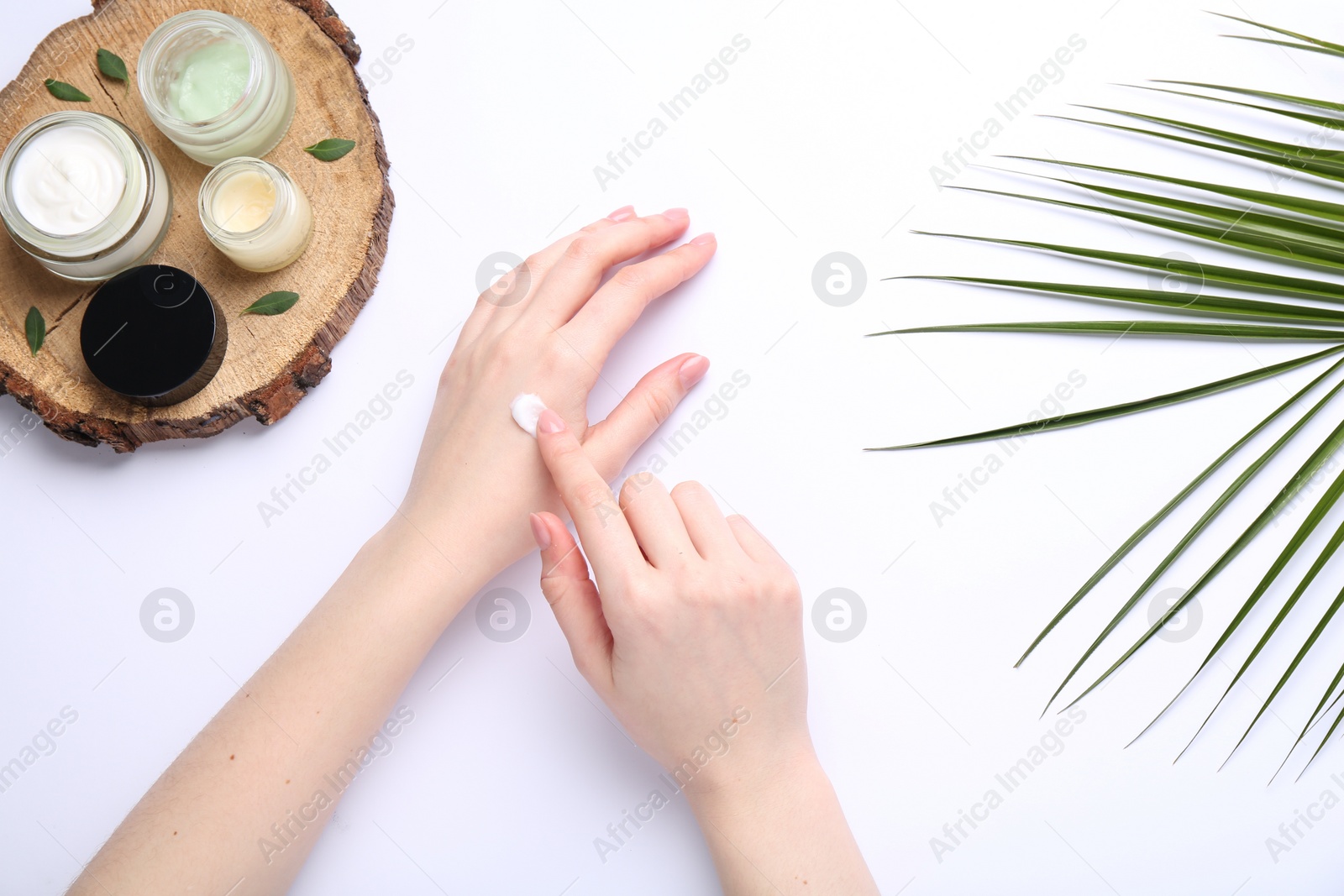 Photo of Woman applying hand cream on white background, top view