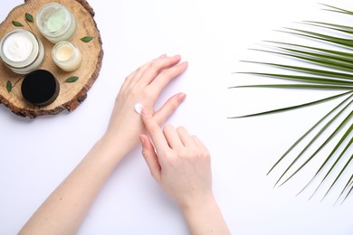 Woman applying hand cream on white background, top view