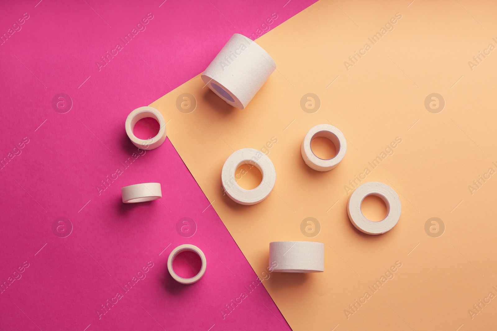 Photo of Sticking plaster rolls on color background, flat lay