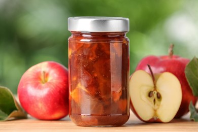 Photo of Delicious apple jam and fresh fruits on wooden table