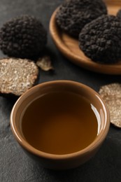 Photo of Bowl of truffle oil on grey table, closeup