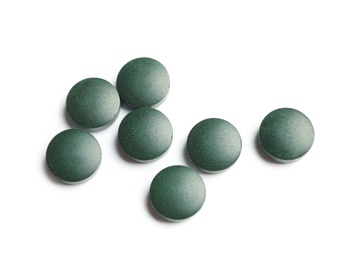 Photo of Spirulina tablets on white background. Healthy lifestyle