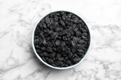 Photo of Bowl with raisins on marble background, top view. Dried fruit as healthy snack