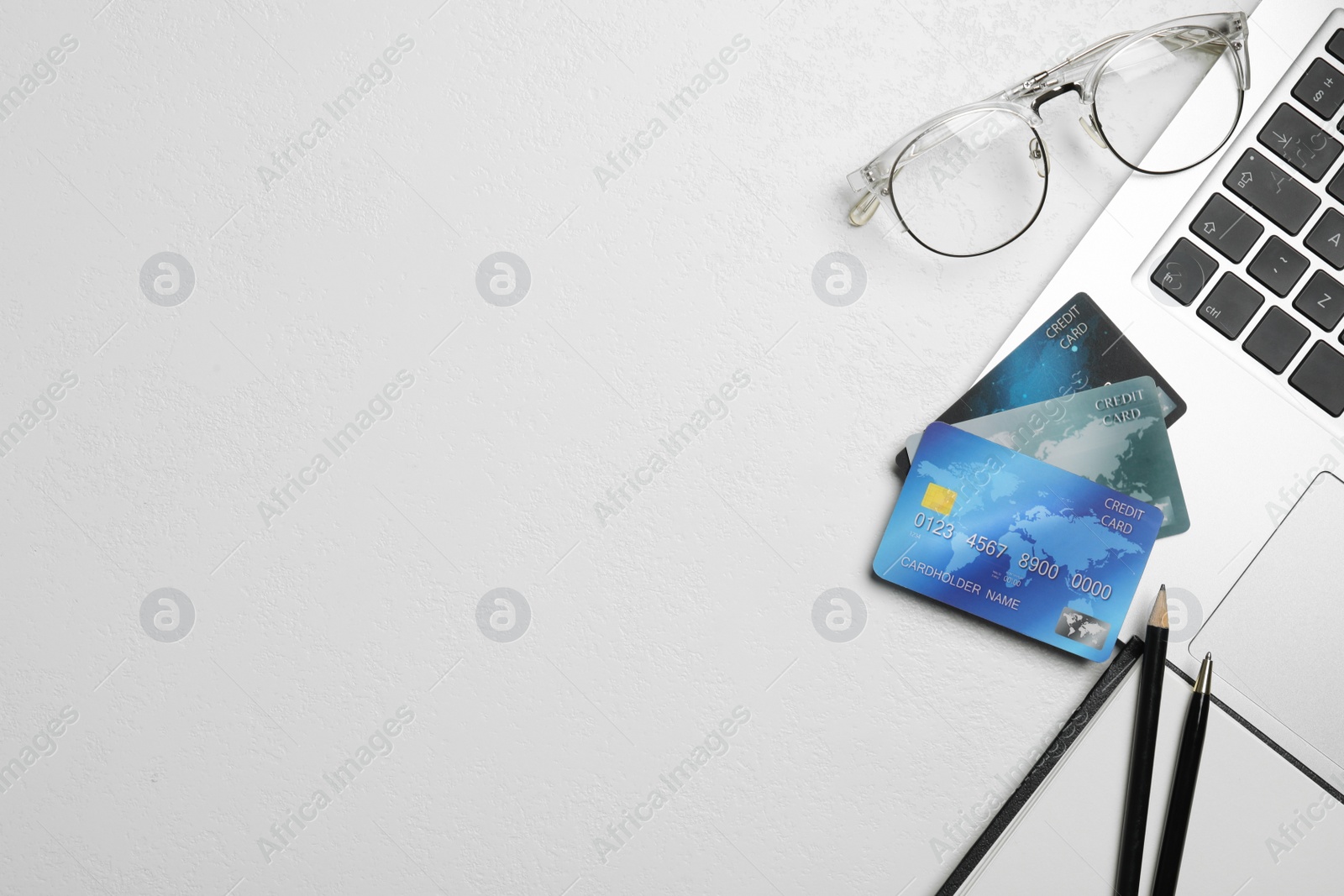 Photo of Flat lay composition with credit cards and laptop on white table. Space for text