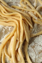 Photo of Raw homemade pasta and flour on table, closeup