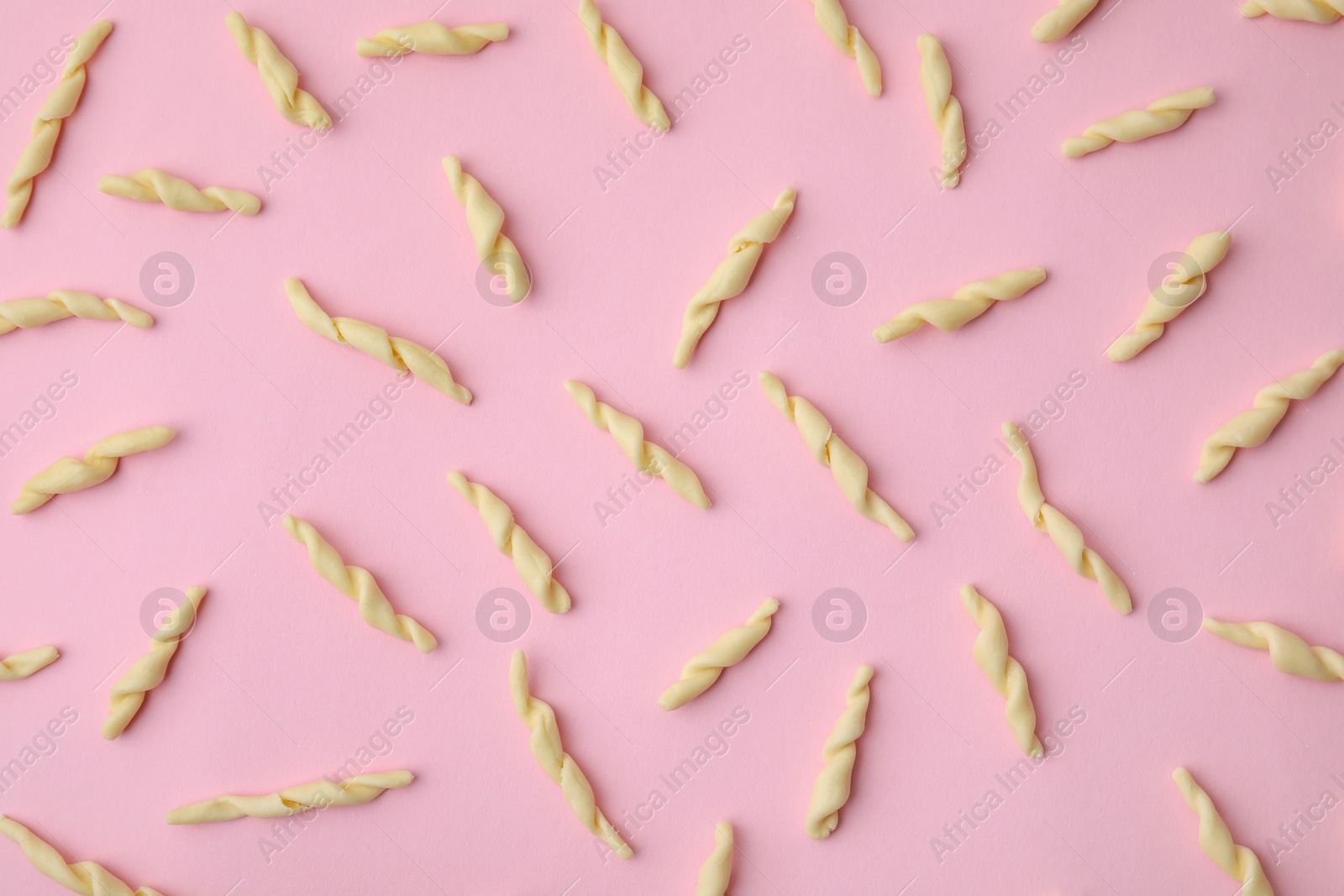 Photo of Uncooked trofie pasta on pink background, flat lay
