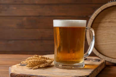 Photo of Glass mug with cold tasty beer and malt on wooden table