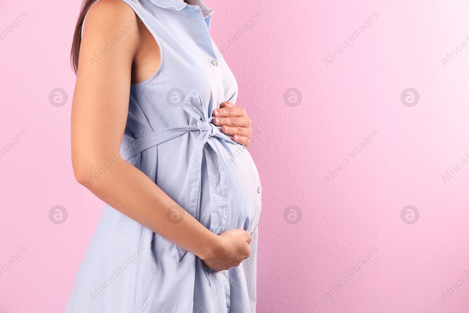 Photo of Pregnant woman posing on color background, closeup. Space for text