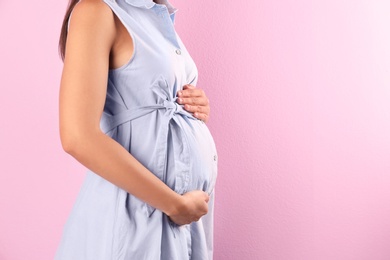 Pregnant woman posing on color background, closeup. Space for text