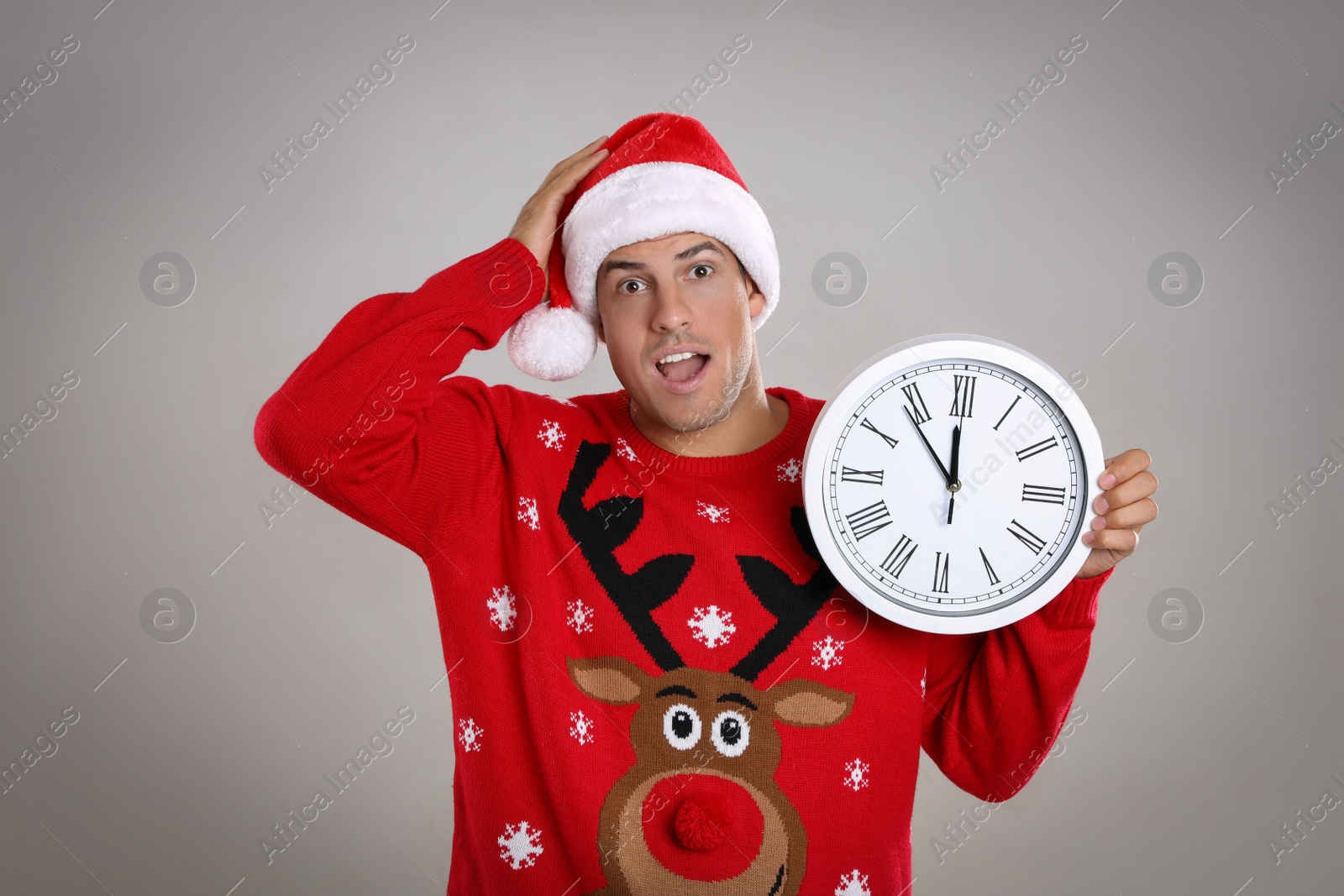 Photo of Man in Santa hat with clock on grey background. New Year countdown