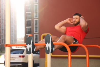 Photo of Man doing abs exercise on parallel bars at outdoor gym