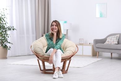 Attractive young woman sitting in armchair at home