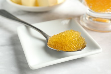 Photo of Fresh pike caviar in spoon on white marble table, closeup