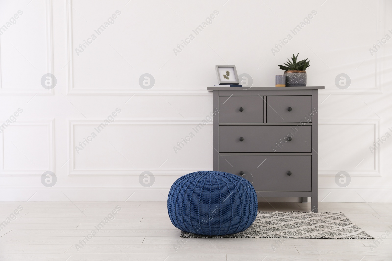 Photo of Stylish room interior with grey chest of drawers and blue pouf, space for text