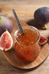 Photo of Glass jar with tasty sweet jam and fresh figs on wooden table