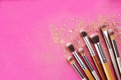 Photo of Makeup brushes and scattered eye shadows on bright 
pink background, flat lay. Space for text