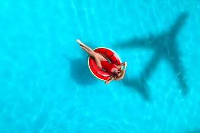 Shadow of airplane and happy woman on inflatable ring in swimming pool, top view. Summer vacation