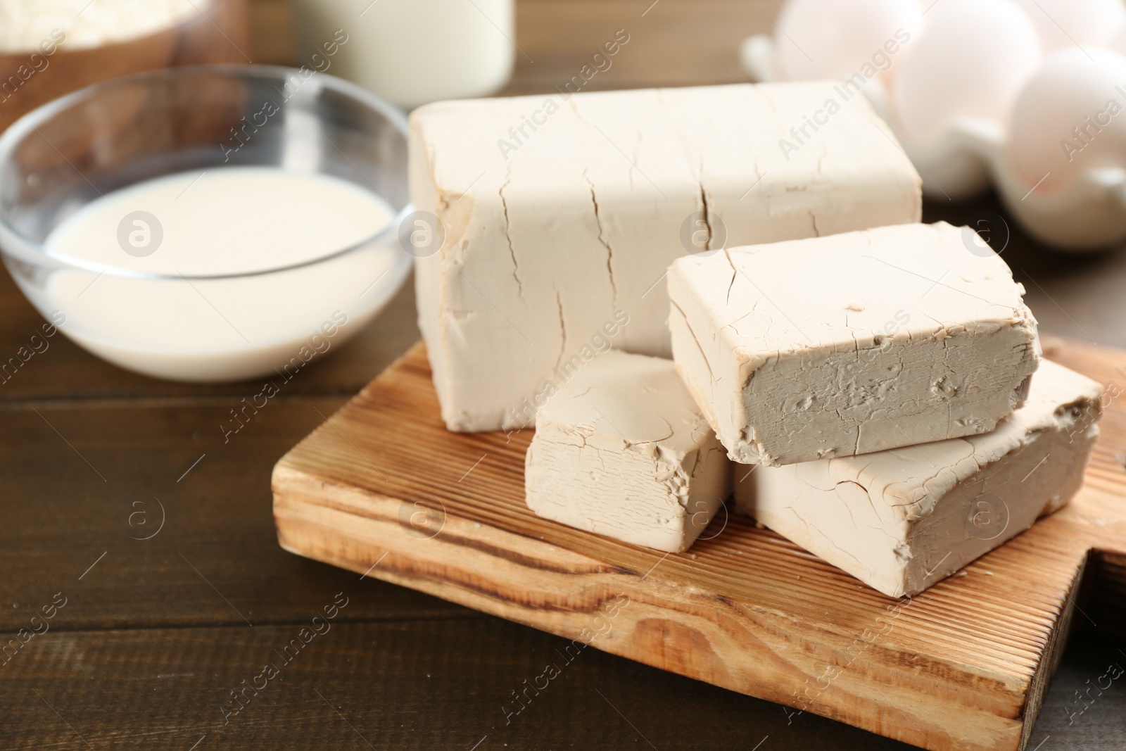 Photo of Pieces of compressed yeast on wooden table, closeup