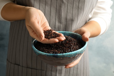 Photo of Woman with bowl of uncooked black rice, closeup