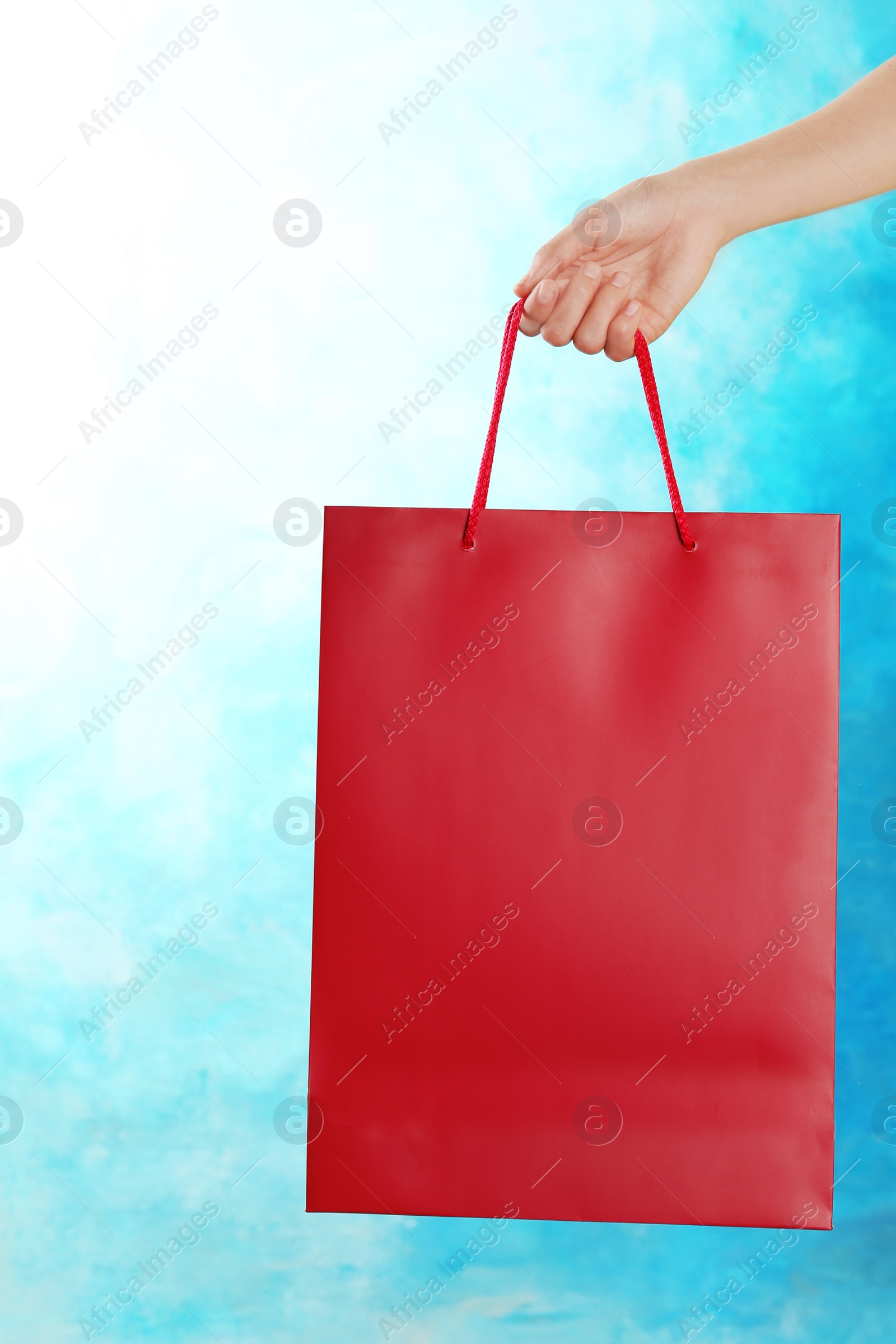 Photo of Woman holding paper shopping bag on color background