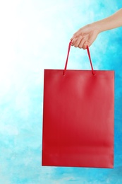 Photo of Woman holding paper shopping bag on color background