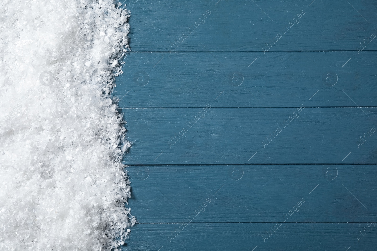Photo of Snow and space for text on blue wooden background, top view. Christmas time