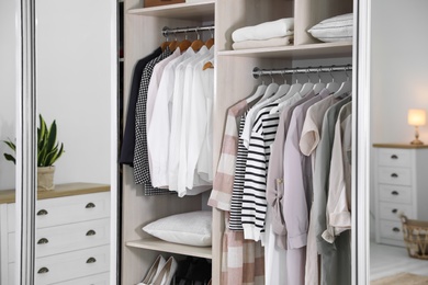 Photo of Wardrobe closet with different stylish clothes in room, closeup