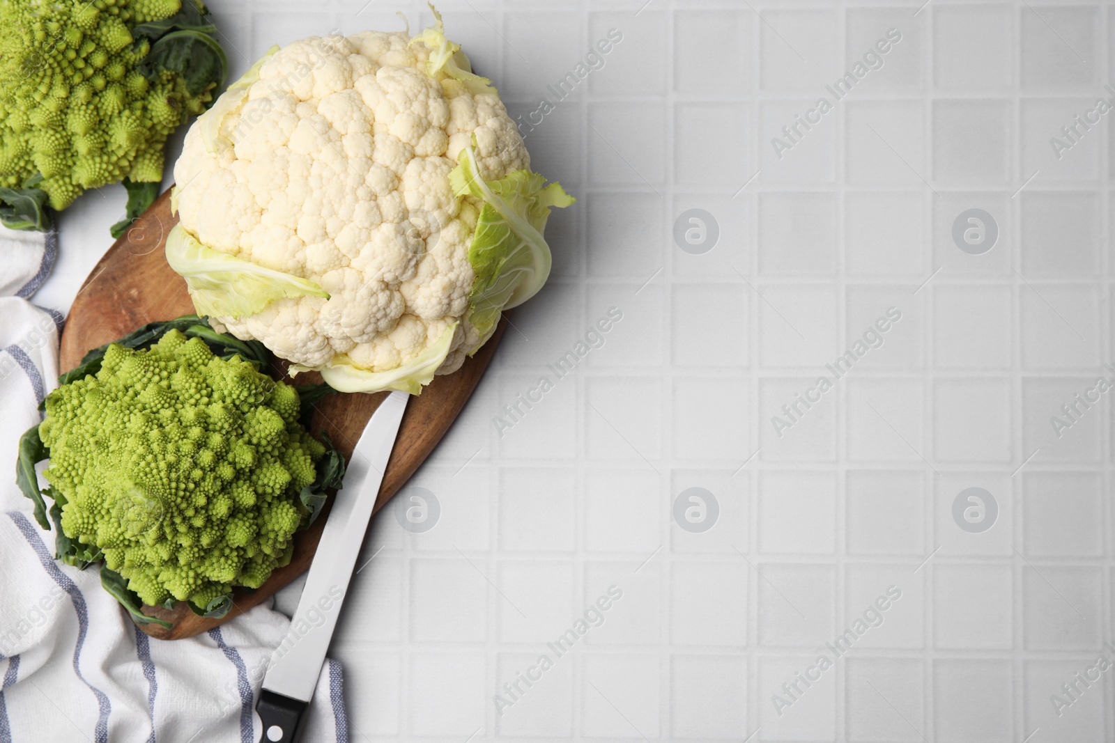 Photo of Fresh Romanesco broccoli and cauliflower on white tiled table, flat lay. Space for text