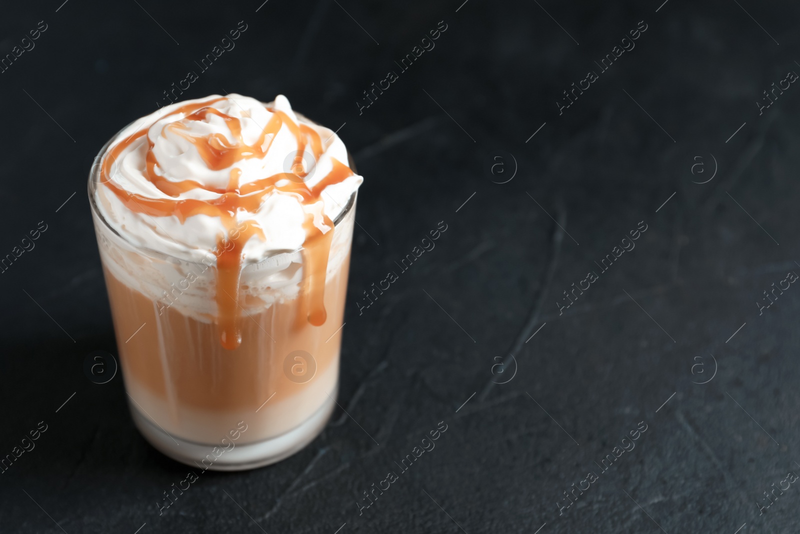 Photo of Glass with delicious caramel frappe on grey background