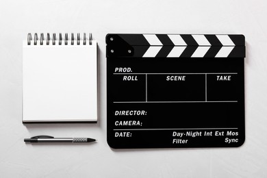 Photo of Movie clapper, notebook and pen on light textured background, flat lay