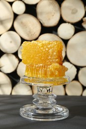 Photo of Glass stand with natural honeycombs on black table
