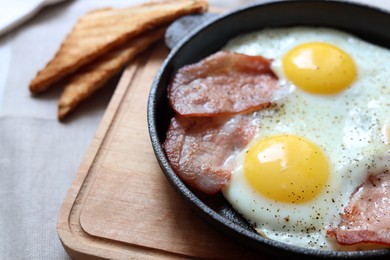 Photo of Tasty fried eggs with bacon on table, closeup. Space for text