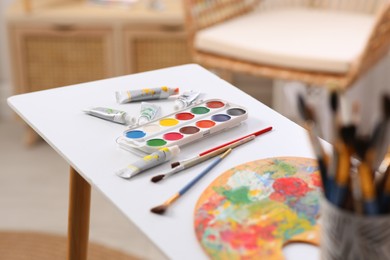 Photo of Brushes and paints on table in art studio