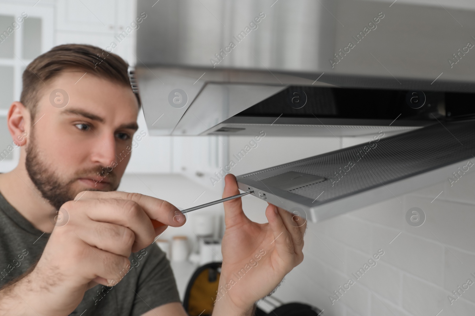 Photo of Man repairing modern cooker hood in kitchen, focus on hands