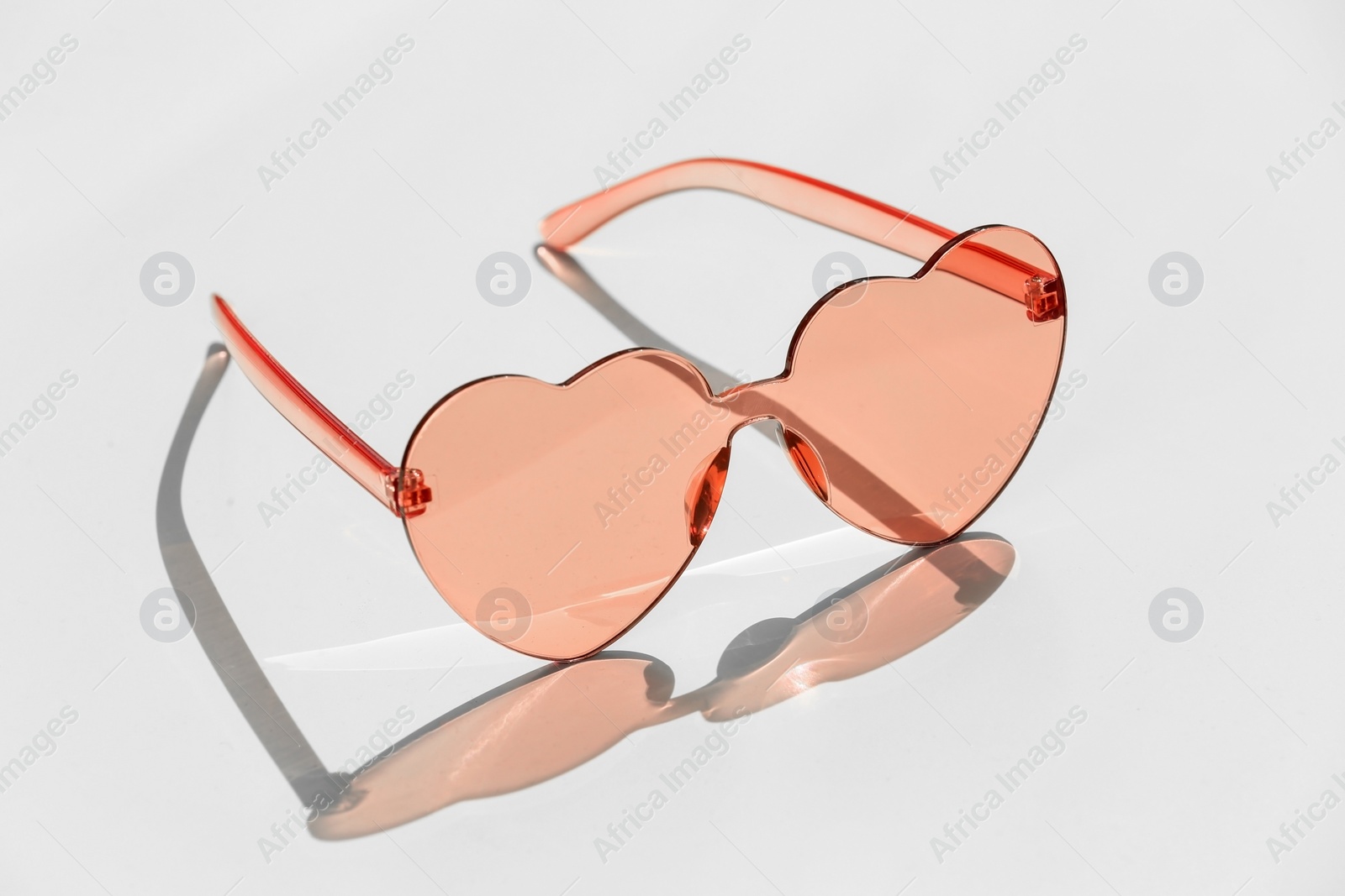 Photo of Stylish heart shaped sunglasses on white background
