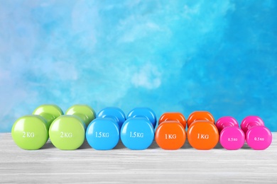 Photo of Many dumbbells on table against color background. Fitness equipment