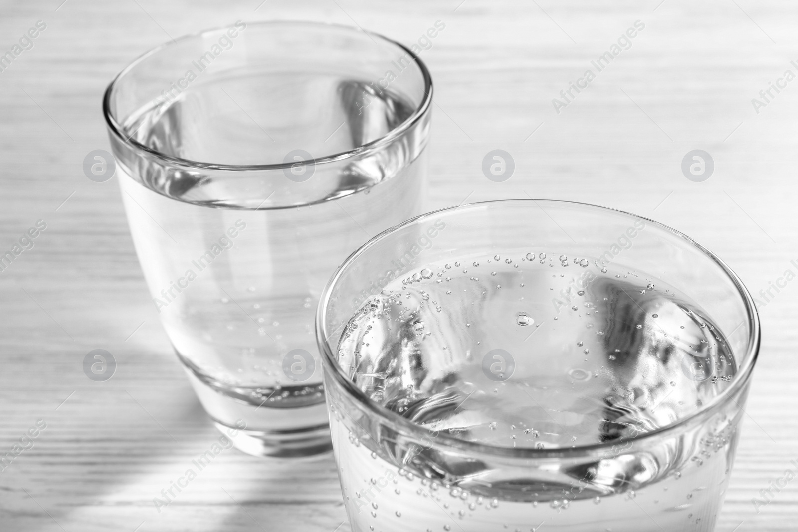 Photo of Glasses of soda water on white wooden table, closeup