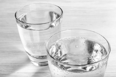 Photo of Glasses of soda water on white wooden table, closeup