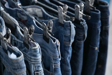 Photo of Metal hangers with different stylish jeans, closeup