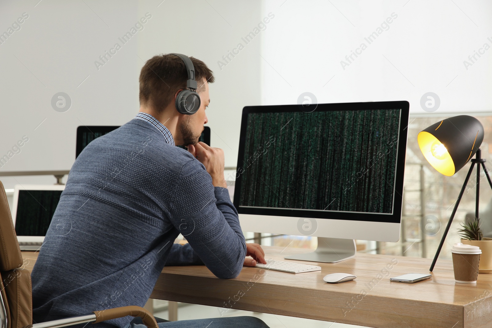 Photo of Programmer with headphones working at desk in office