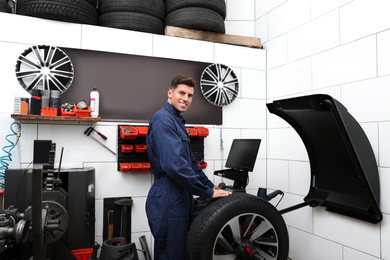 Man working with wheel balancing machine at tire service