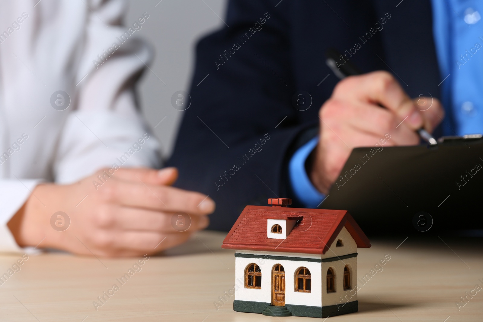 Photo of House model and real estate agent working with client at table, closeup. Home insurance